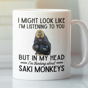 May include: White ceramic mug with a black and white graphic of a monkey. The text on the mug reads "I might look like I'm listening to you, but in my head I'm thinking about Saki Monkeys."
