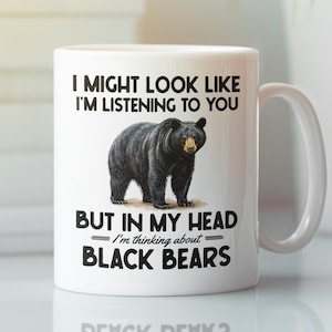 May include: White ceramic mug featuring a black bear illustration and the text "I MIGHT LOOK LIKE I'M LISTENING TO YOU BUT IN MY HEAD I'M THINKING ABOUT BLACK BEARS". The mug has a white handle and is suitable for hot or cold drinks.
