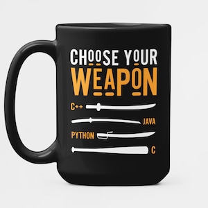 以下が含まれることがあります： 黒いセラミックマグカップ。白とオレンジで「CHOOSE YOUR WEAPON」の文字が書かれています。その下には、C++、Java、Python、Cなどのプログラミング言語がラベル付けされた武器のイラストがあります。