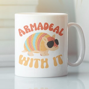 May include: White ceramic mug with a colorful armadillo wearing sunglasses and the text "ARMADEAL WITH IT" in a retro font.