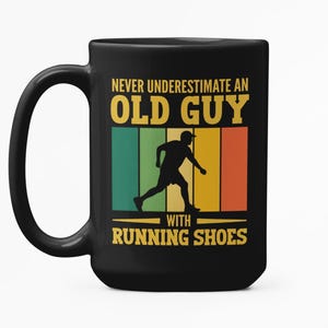 以下が含まれることがあります： 「NEVER UNDERESTIMATE AN OLD GUY WITH RUNNING SHOES」の文字が入った黒いセラミックコーヒーマグ。ランニングする人物のシルエットと、緑、黄、オレンジのレトロなカラーブロックデザインが特徴です。
