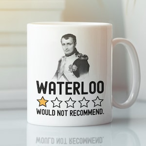 May include: White ceramic mug with a black and white image of Napoleon Bonaparte. The mug has the text "Waterloo" and a one-star rating with the text "Would not recommend."
