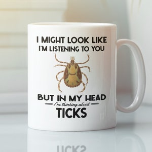 May include: White ceramic mug with a black and white graphic of a tick. The text on the mug reads "I might look like I'm listening to you, but in my head I'm thinking about ticks."