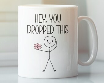 May include: White ceramic mug with a black and white illustration of a stick figure holding a pink brain. The mug has the text "Hey, you dropped this" printed on it.