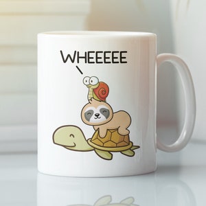 May include: White ceramic mug with a cartoon illustration of a sloth riding a turtle with a snail on top. The text "WHEEEEEE" is written above the animals.