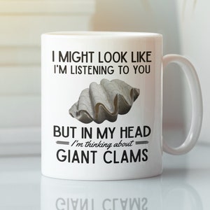 May include: White ceramic coffee mug with a black graphic that reads "I might look like I'm listening to you but in my head I'm thinking about giant clams". The graphic also includes a picture of a clam shell.