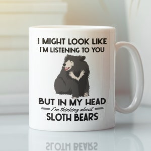 Peut inclure: Une tasse en céramique blanche avec une illustration noire d'un ours paresseux. La tasse porte l'inscription "Je peux avoir l'air d'écouter, mais dans ma tête je pense aux ours paresseux."