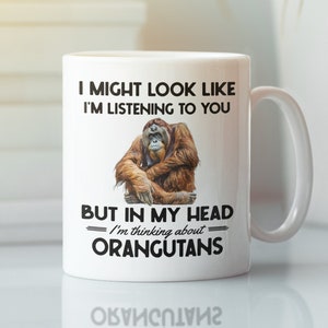 May include: White ceramic mug with a black and white graphic of an orangutan. The text on the mug reads "I might look like I'm listening to you but in my head I'm thinking about orangutans."