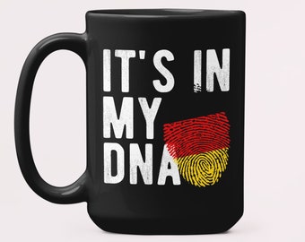 May include: Black ceramic coffee mug with a white design that says "It's in my DNA" with a fingerprint graphic of the German flag.