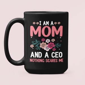 May include: Black ceramic coffee mug with the text "I AM A MOM AND A CEO NOTHING SCARES ME" in pink and white, with floral accents. The mug has a large handle and a glossy finish.