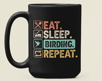 May include: Black coffee mug with a white graphic that reads "Eat. Sleep. Birding. Repeat."