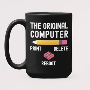 Könnte beinhalten: Schwarze Kaffeetasse mit einer weißen Grafik eines Bleistifts mit dem Text "The Original Computer" und den Wörtern "Print", "Delete" und "Reboot" unter dem Bleistift.