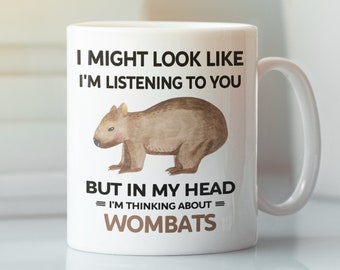 Op de afbeelding: Een witte keramische mok met een zwart-witte illustratie van een wombat. De mok heeft de tekst "Ik kan eruit zien alsof ik luister, maar in mijn hoofd denk ik aan wombats."