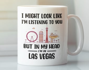 May include: White ceramic coffee mug with a black graphic of a Las Vegas skyline and the text "I might look like I'm listening to you, but in my head I'm in Las Vegas."