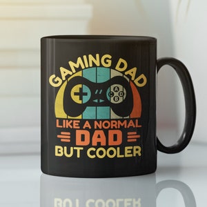 Könnte beinhalten: Schwarze Kaffeetasse mit einem Retro-Design mit einem Videospiel-Controller und dem Text "Gaming Dad Like a Normal Dad But Cooler".