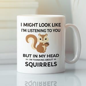 May include: White ceramic mug with a black and brown squirrel graphic. The mug reads "I might look like I'm listening to you, but in my head = I'm thinking about = squirrels."