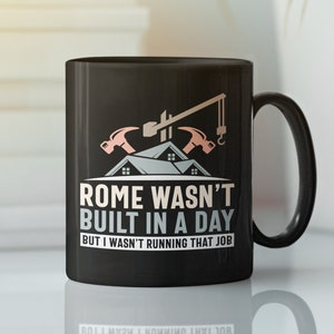 May include: Black coffee mug with a graphic of a house under construction and the text "Rome wasn't built in a day but I wasn't running that job".