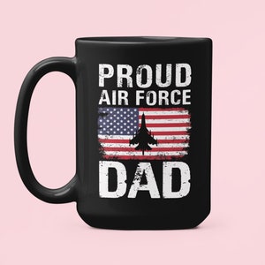May include: Black ceramic coffee mug with a white design that says "Proud Air Force Dad" with an American flag and a fighter jet graphic.