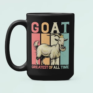 May include: Black ceramic mug featuring a goat illustration with the text "GOAT GREATEST OF ALL TIME" in a retro style. The goat is depicted with a crown and long beard, set against a striped background of pink, orange, teal, and beige.