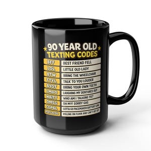 May include: Black ceramic mug with the text "90 YEAR OLD TEXTING CODES" and a list of acronyms with their meanings. The mug has a large handle and a glossy finish. The text is in white and yellow.