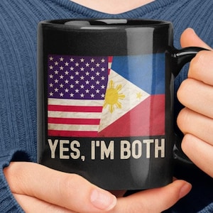 May include: Black coffee mug with a white handle. The mug features a split image of the American and Philippine flags with the text "YES, I'M BOTH" printed below.