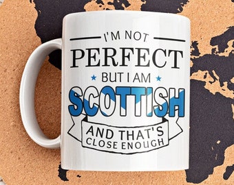 May include: White ceramic mug with a black and blue design that says "I'm not perfect but I am Scottish and that's close enough". The mug is sitting on a cork coaster with a black world map design.