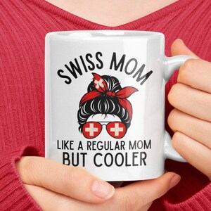May include: White ceramic mug with a black and red design. The mug features a woman with a messy bun and sunglasses, and the text "Swiss Mom Like a Regular Mom But Cooler".
