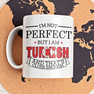 May include: White ceramic coffee mug with the text "I'm not perfect but I am Turkish and that's close enough" printed on it. The mug is sitting on a cork coaster with a world map design.
