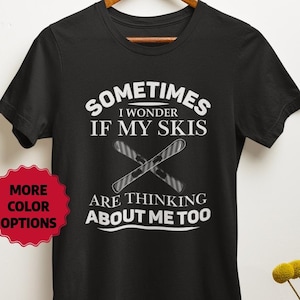 May include: Black t-shirt with white text that reads "Sometimes I wonder if my skis are thinking about me too."  The text is surrounded by a graphic of two crossed skis.
