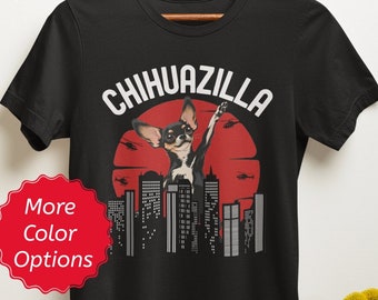 May include: Black t-shirt with a chihuahua wearing sunglasses and a red bandana, standing on a city skyline with the text "Chihuazilla" above it. The text "More Color Options" is in a red circle.