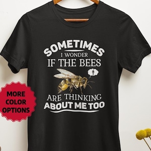 May include: Black t-shirt with white text that reads "Sometimes I wonder if the bees are thinking about me too." A bee is pictured above the text. The text "More Color Options" is in a red circle in the lower left corner of the image.