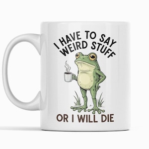 Może przedstawiać: Biały ceramiczny kubek z zabawnym wzorem. Kubek przedstawia kreskówkową żabę trzymającą filiżankę kawy z czarnym napisem "I HAVE TO SAY WEIRD STUFF OR I WILL DIE". Żaba jest zielona, a filiżanka biała.