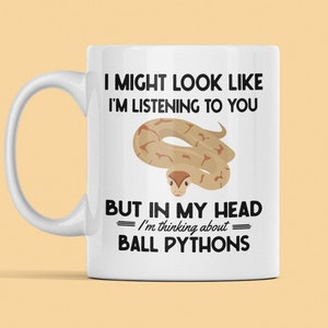 May include: White ceramic coffee mug with a black and white graphic of a snake and the text "I might look like I'm listening to you but in my head I'm thinking about ball pythons."
