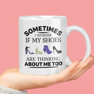 May include: White ceramic mug with a black graphic that reads "Sometimes I wonder if my shoes are thinking about me too". The graphic includes a row of five different shoe icons.