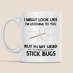 May include: White ceramic mug with a black and white graphic of a stick insect. The text reads "I might look like I'm listening to you, but in my head I'm thinking about stick bugs."