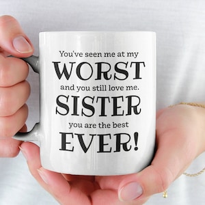 May include: White ceramic mug with black text that reads "You've seen me at my WORST and you still love me. SISTER you are the best EVER!". The mug is held by a person.