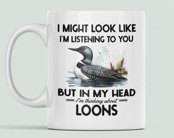 May include: White ceramic coffee mug with a black and white illustration of a loon on water. The text reads "I might look like I'm listening to you, but in my head I'm thinking about loons."