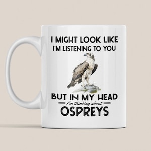Peut inclure: Une tasse à café en céramique blanche avec une image en noir et blanc d'un balbuzard pêcheur et le texte "I might look like I'm listening to you but in my head I'm thinking about Ospreys".