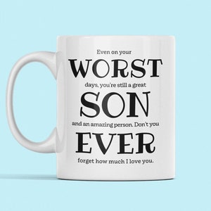 Puede incluir: Taza de cerámica blanca con texto negro que dice "Incluso en tus peores días, sigues siendo un gran HIJO y una persona increíble. Nunca olvides cuánto te quiero."
