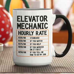 Może przedstawiać: Biały ceramiczny kubek z czarnym uchwytem i obramowaniem. Kubek zawiera tekst "ELEVATOR MECHANIC HOURLY RATE" z listą stawek godzinowych dla różnych poziomów pomocy. Czerwony i biały pojemnik w kropki znajduje się w tle.