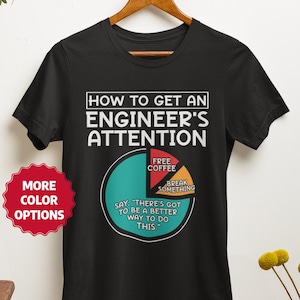 May include: A black short-sleeve t-shirt featuring a white graphic of a pie chart titled HOW TO GET AN ENGINEER'S ATTENTION. The chart segments are labelled FREE COFFEE, BREAK SOMETHING, and SAY THERE'S GOT TO BE A BETTER WAY TO DO THIS.