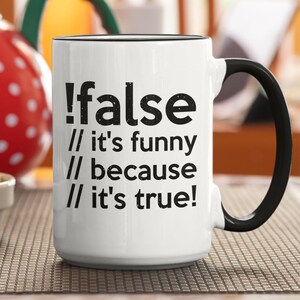 Könnte beinhalten: Weiße Keramik-Tasse mit schwarzem Henkel und Rand. Die Tasse trägt den Text "!false // it's funny // because // it's true!" in Schwarz. Ein roter Topf mit weißen Punkten und ein Teller mit Keksen sind im Hintergrund.