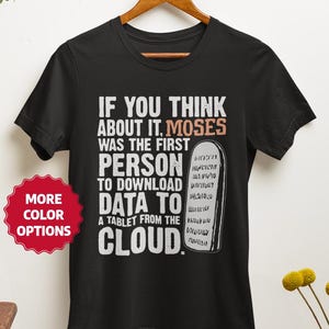 May include: Black t-shirt with white text that reads "IF YOU THINK ABOUT IT, MOSES WAS THE FIRST PERSON TO DOWNLOAD DATA TO A TABLET FROM THE CLOUD." A red sticker with "MORE COLOR OPTIONS" is on the left.