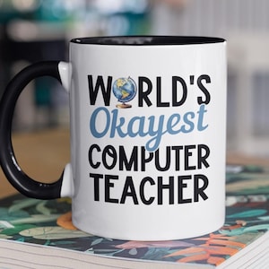Puede incluir: Taza de cerámica blanca con borde y asa negros. La taza tiene un gráfico que dice "WORLD'S Okayest COMPUTER TEACHER" con un pequeño gráfico de globo terráqueo sobre la palabra "Okayest".