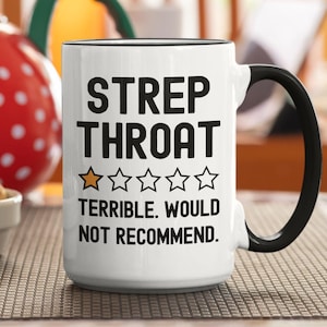 May include: White ceramic mug with black handle and rim. The mug features the words "STREP THROAT" in bold black letters, with a rating of one star and the text "TERRIBLE. WOULD NOT RECOMMEND."