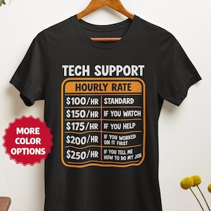 May include: Black t-shirt with the text "TECH SUPPORT HOURLY RATE" and a price chart. The chart lists hourly rates from £79 to £198 based on the level of assistance provided. A red sticker with "MORE COLOR OPTIONS" is visible.