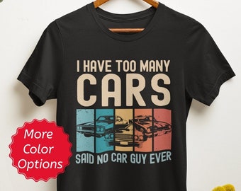May include: Black t-shirt with a vintage-style graphic that says "I have too many cars said no car guy ever". The graphic features a row of three classic cars in a rainbow color scheme.