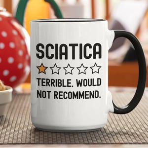 May include: A white ceramic mug with a black handle and the text "But First, Coffee" in a black, handwritten-style font. The mug is on a white surface.