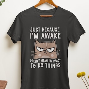 May include: Black t-shirt with a cartoon cat and the text "Just because I'm awake doesn't mean I'm ready to do things".