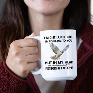 May include: White ceramic mug with a black graphic of a peregrine falcon in flight. The text reads "I might look like I'm listening to you, but in my head I'm thinking about Peregrine Falcons."